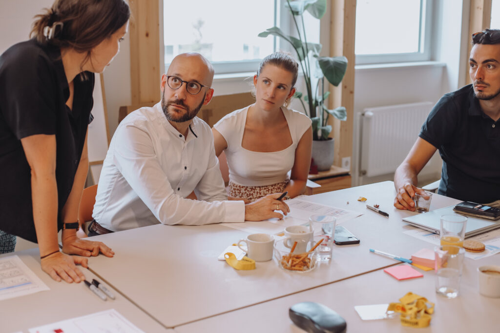 Better Mobility Workshop mit Postbus zur Verbesserung des Angebots - Team sitzt am Tisch gemeinsam mit Claudia aus dem Team von POINT&